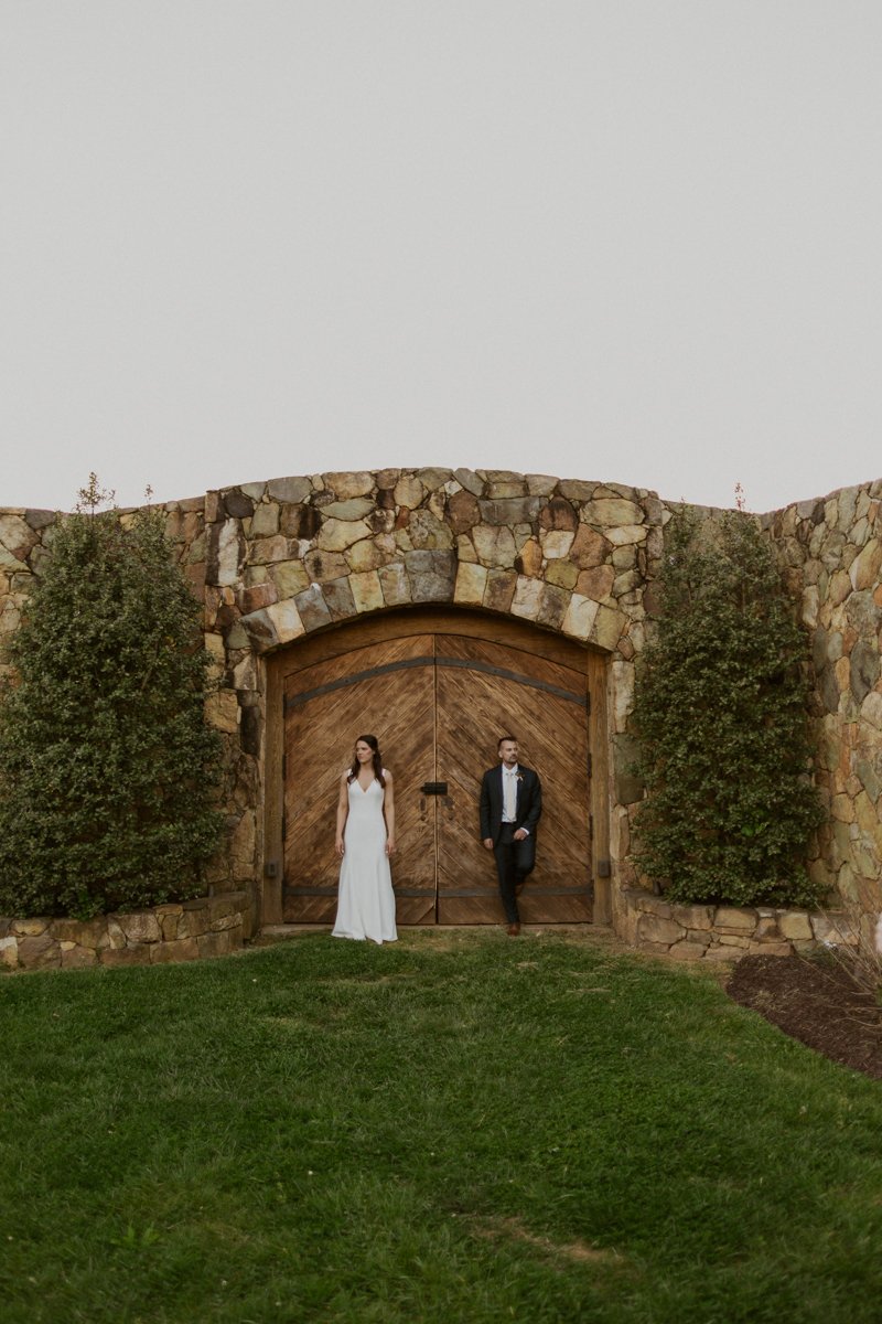 Bride and groom standing infront of rustic wood doors of Stone Tower Winery.