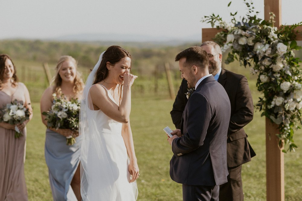Bride laughs with her groom during their wedding vows. 