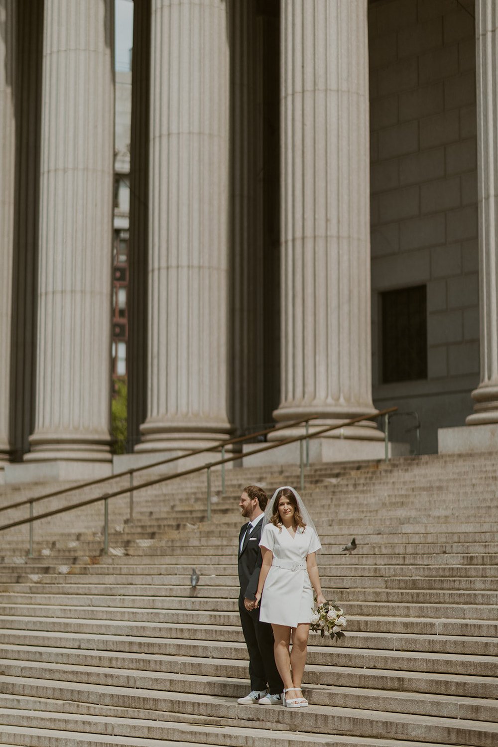 Husband and wife standing on the stairs of the NYC courthouse.