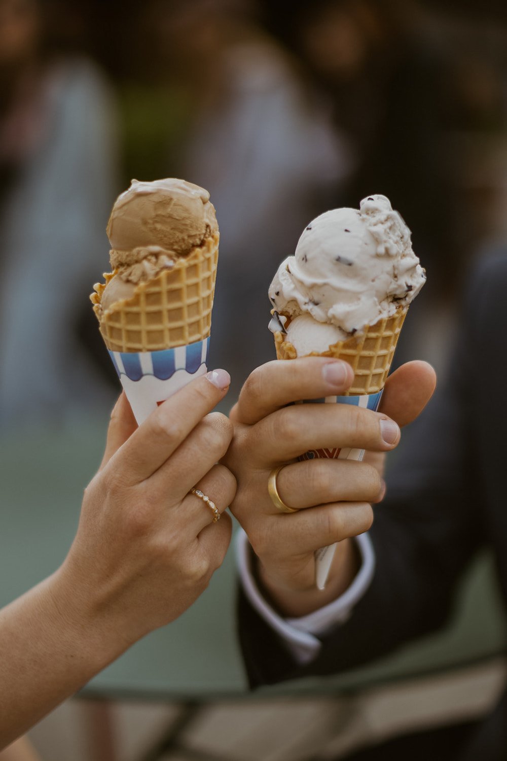 The couple cheers their ice cream cones together.