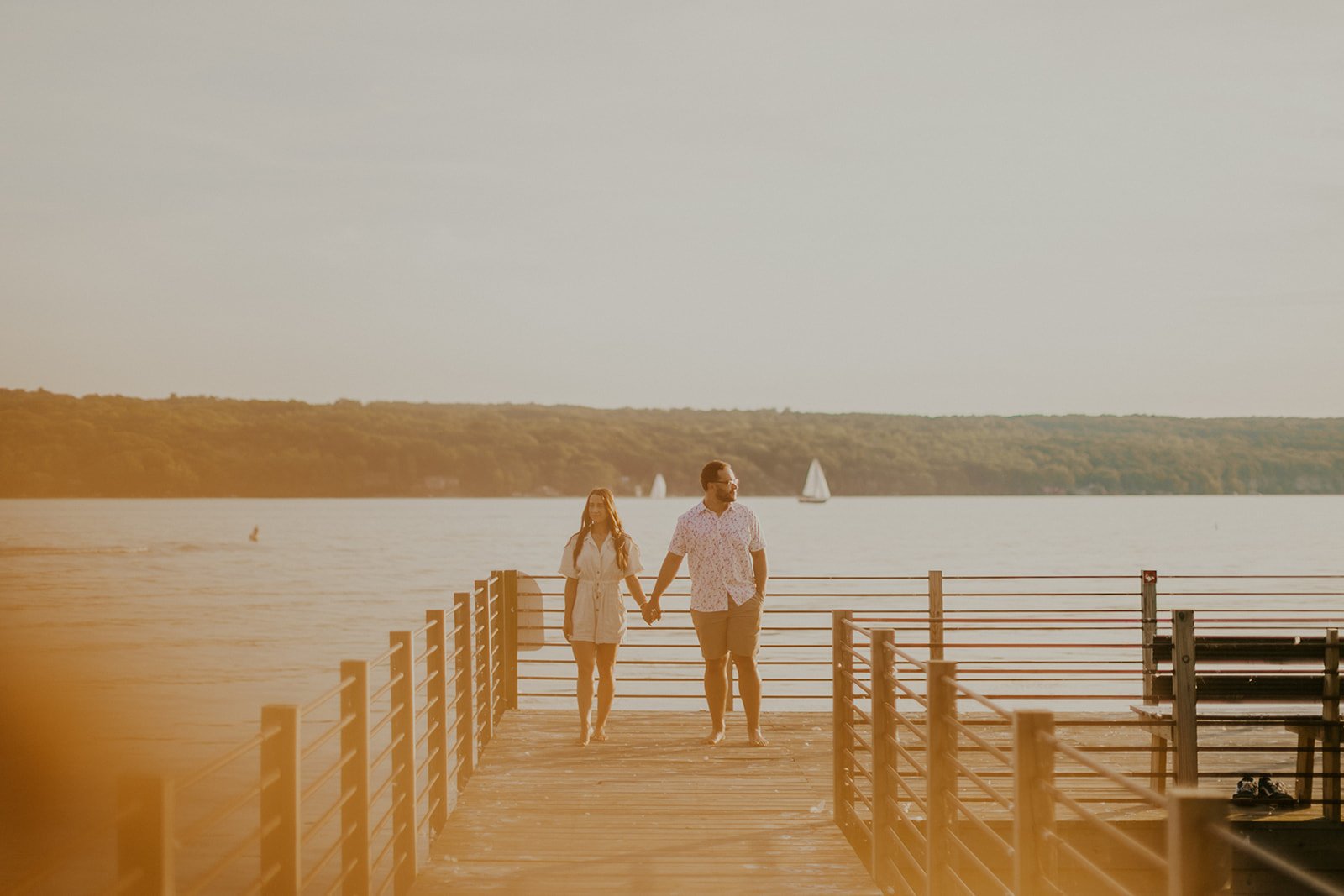 Couple standing on the pier holding hands during the golden hour.