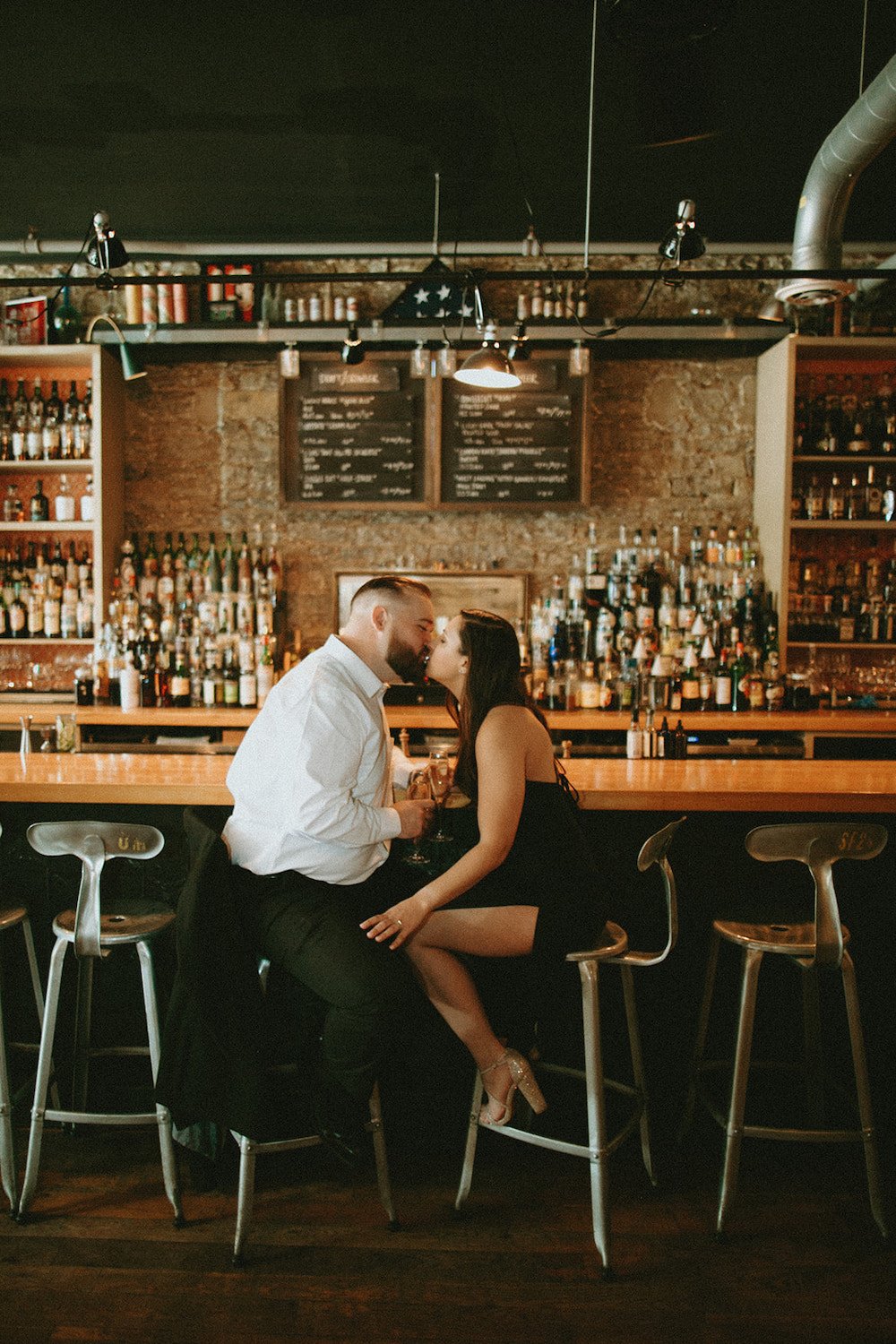 Couple sharing a kiss at the bar of Hand in Foot.