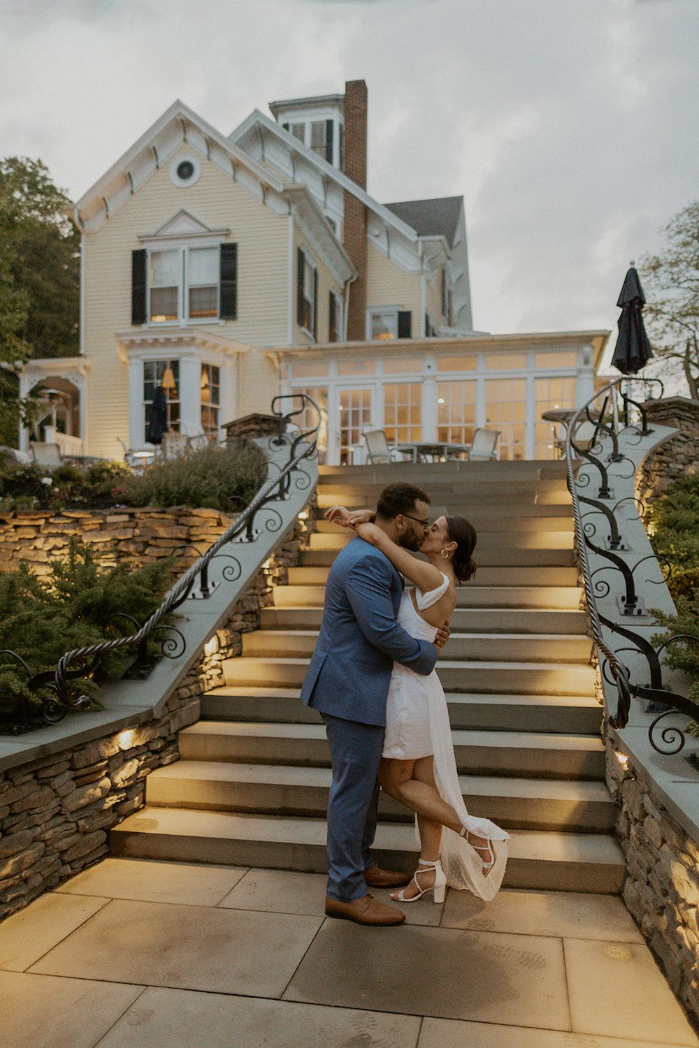 Bride shares a kiss with her groom infront of the stairs at the Inn at Taughannock.