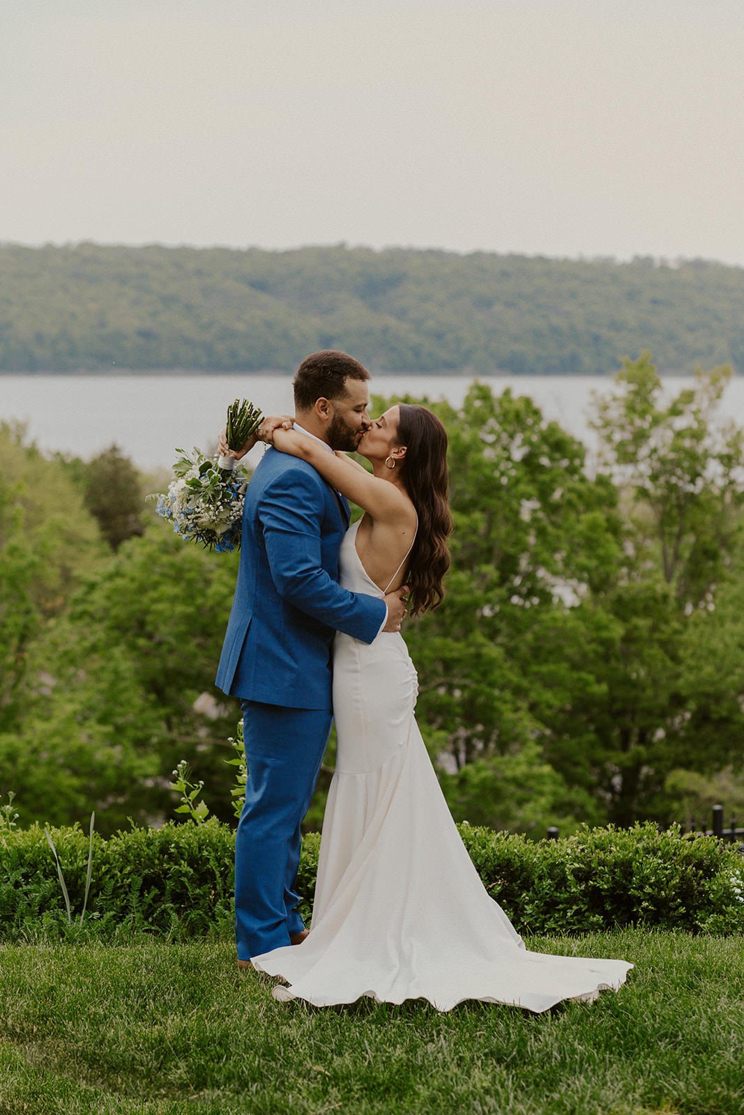 Bride and groom share a kiss with the backdrop of the lake. 