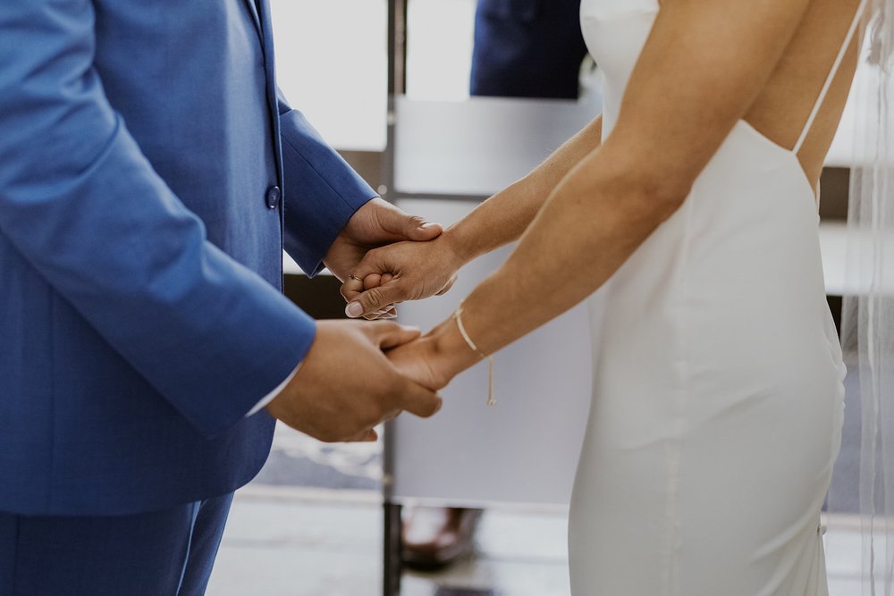 Bride and groom hold hands during their wedding ceremony.