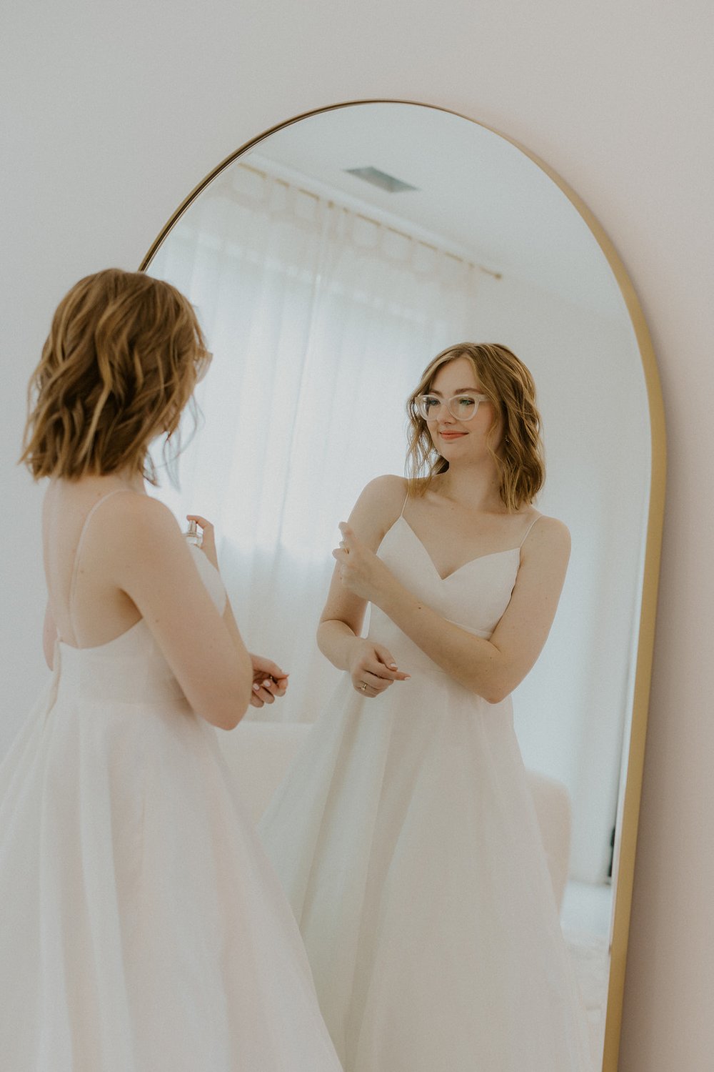 Bride spritzing herself in the mirror with her favorite bridal perfume.