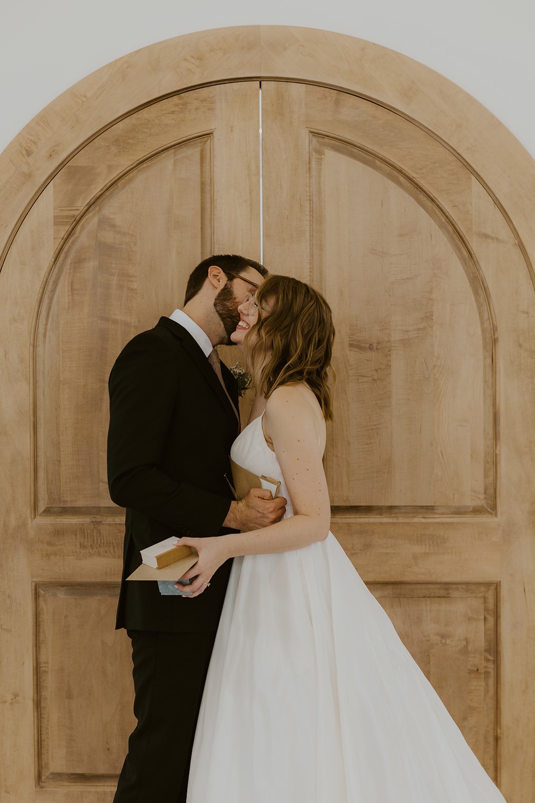 Groom kisses his bride on the cheek after sharing a token from one another. 