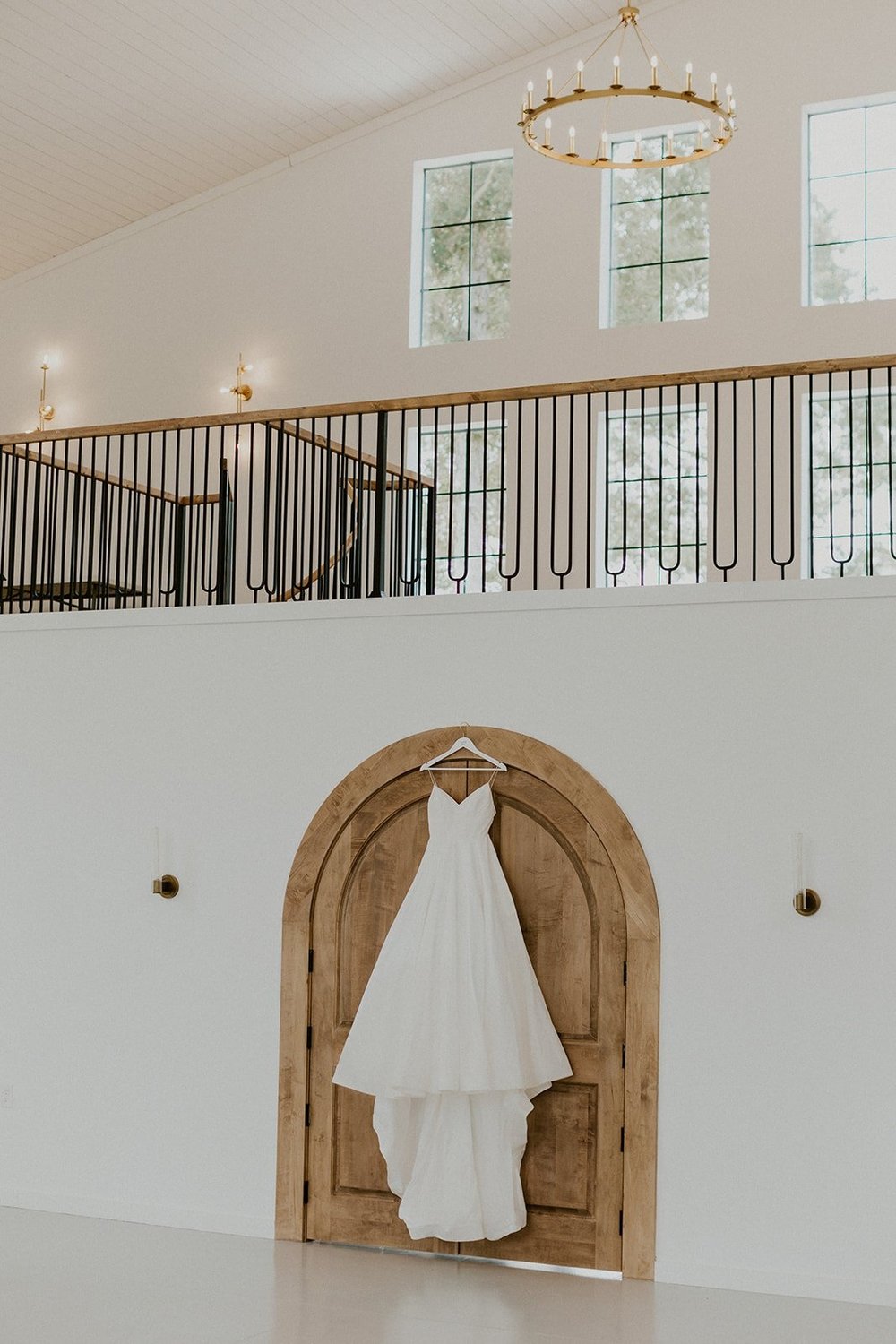 Wedding dress hanging in front of wood doors at wedding venue. 