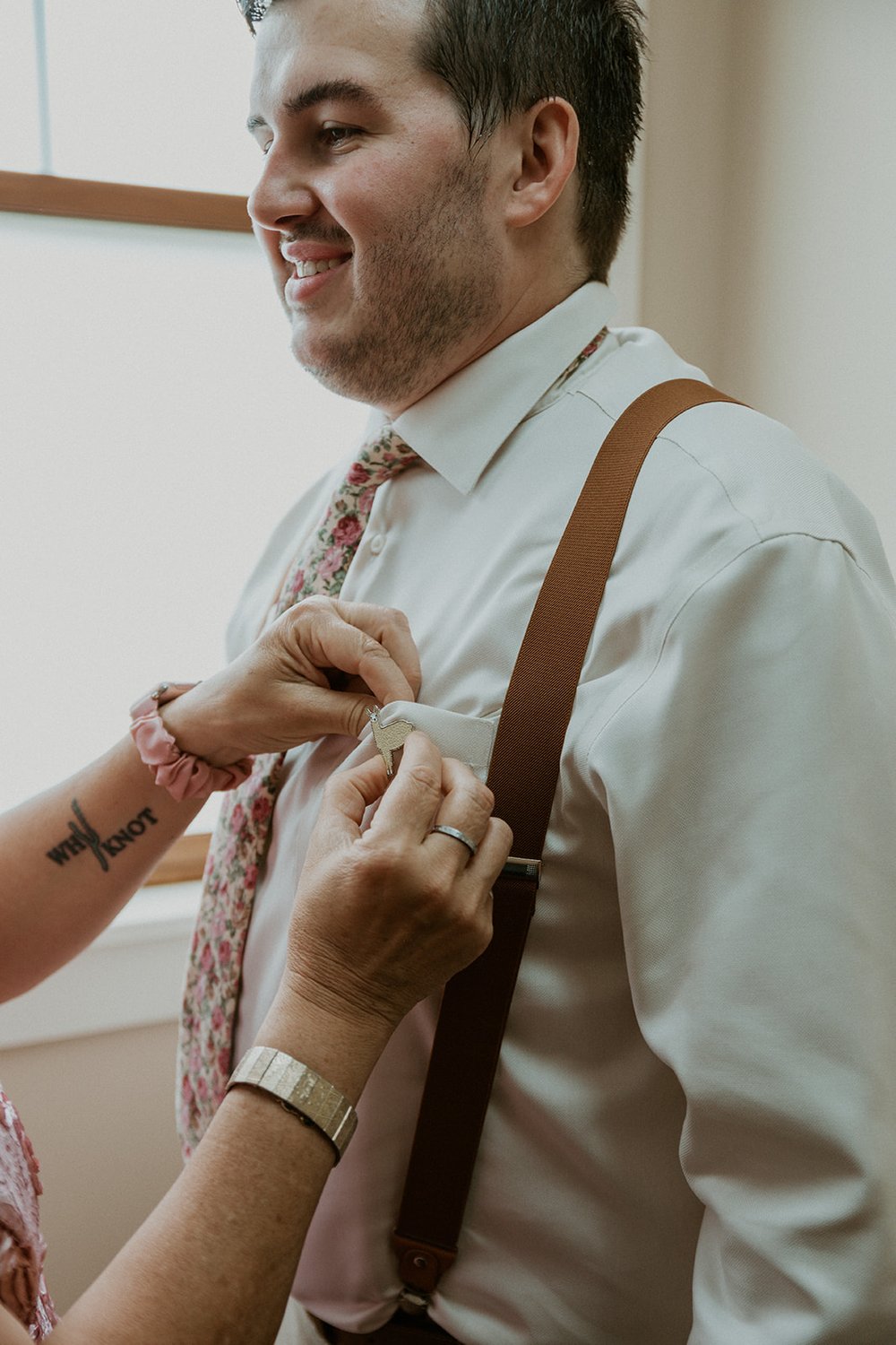 Mother of the groom attaches the boutonniere to the grooms shirt.