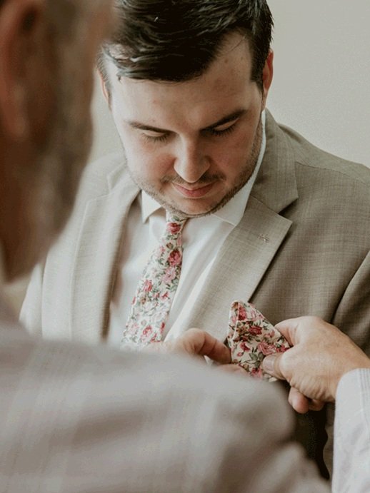 Father of the groom carefully places his handkerchief into his suit jacket.  