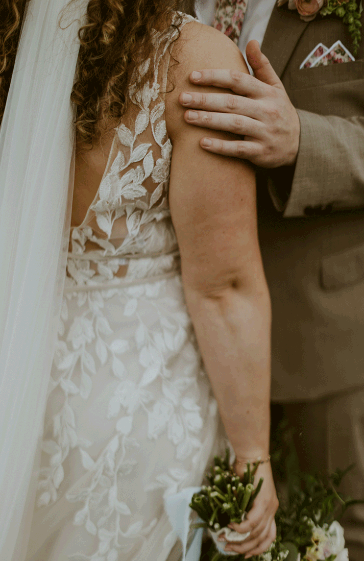 Groom graces his bride's arm with his hand.