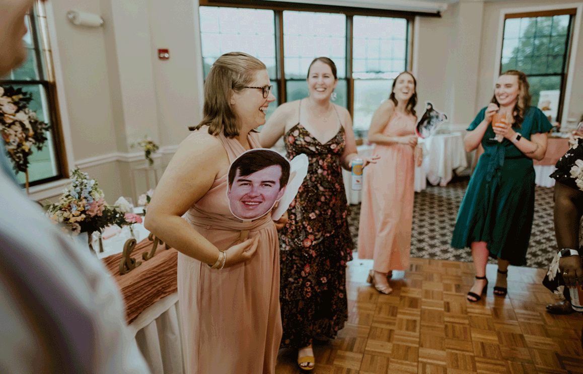 Bridesmaid dances while holding photos of the bride and groom in her gown.