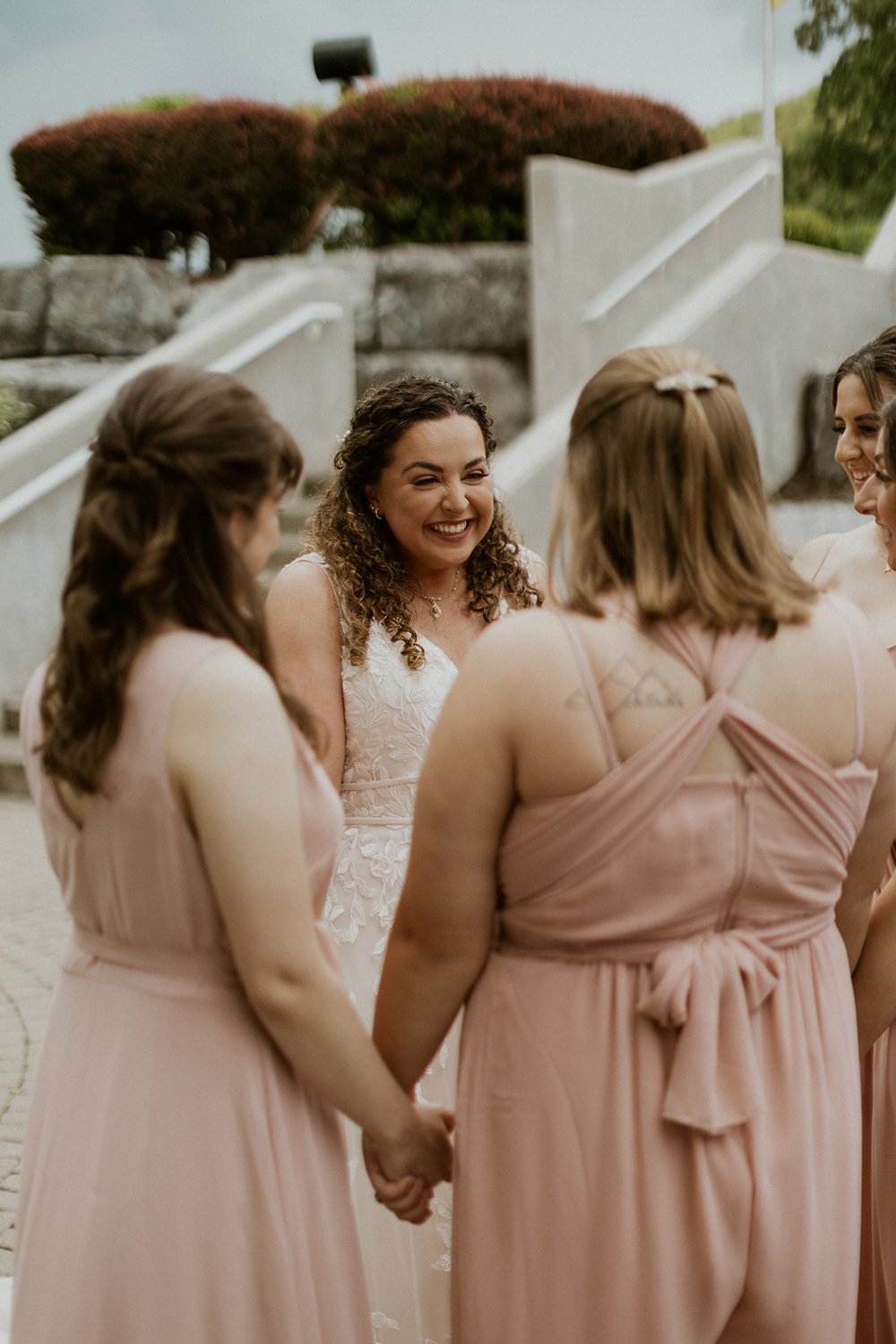 Bride holds her bridesmaids hands while smiling with excitement. 