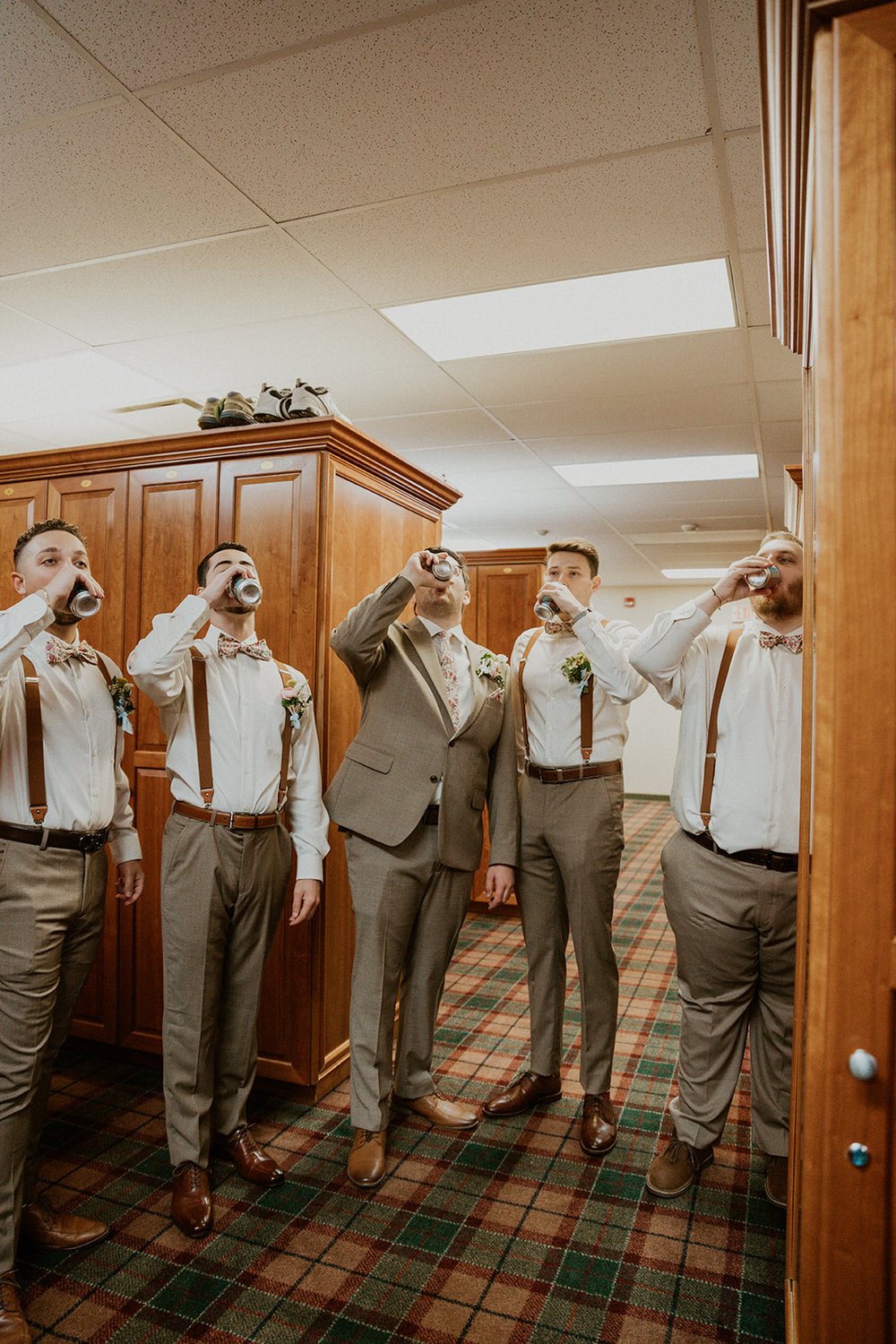 Groomsmen shotgun a beverage in the suite before the wedding festivities. 