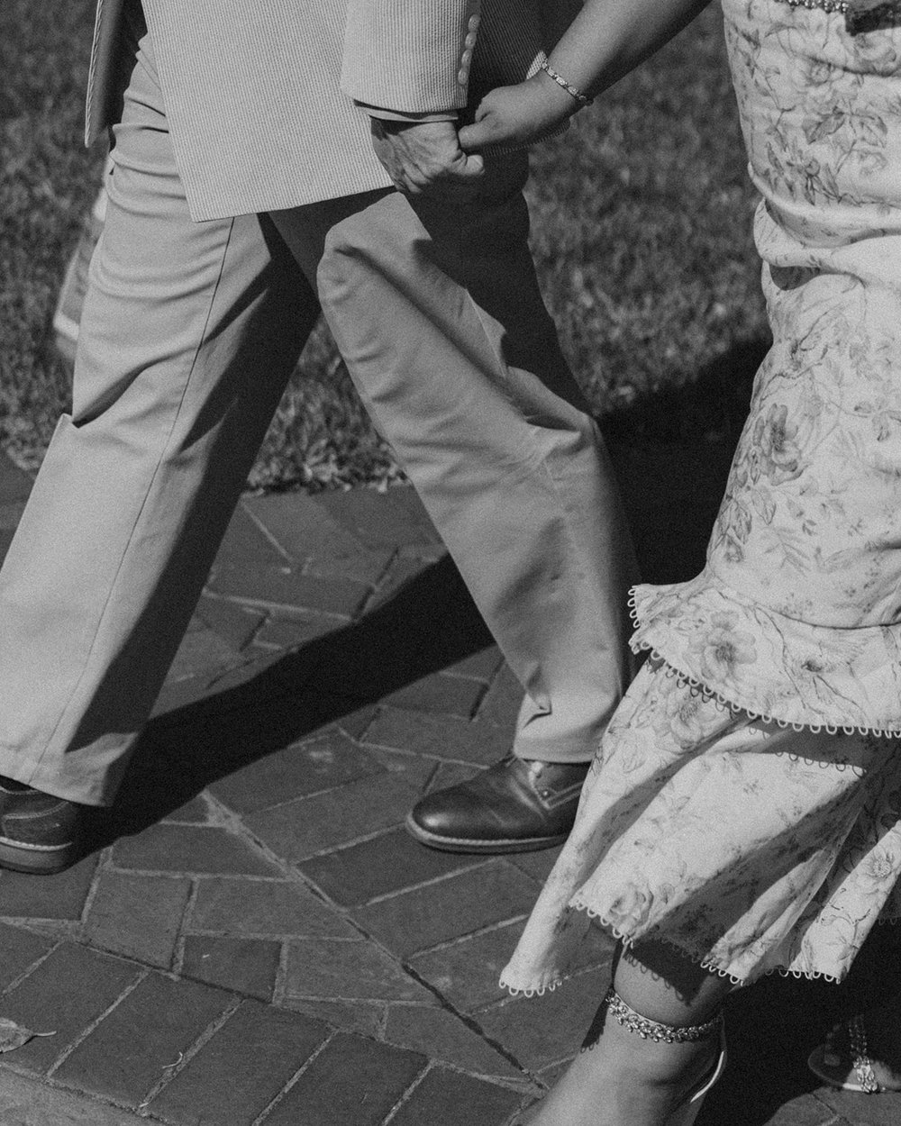 The couple hand in hand walking through the gardens.