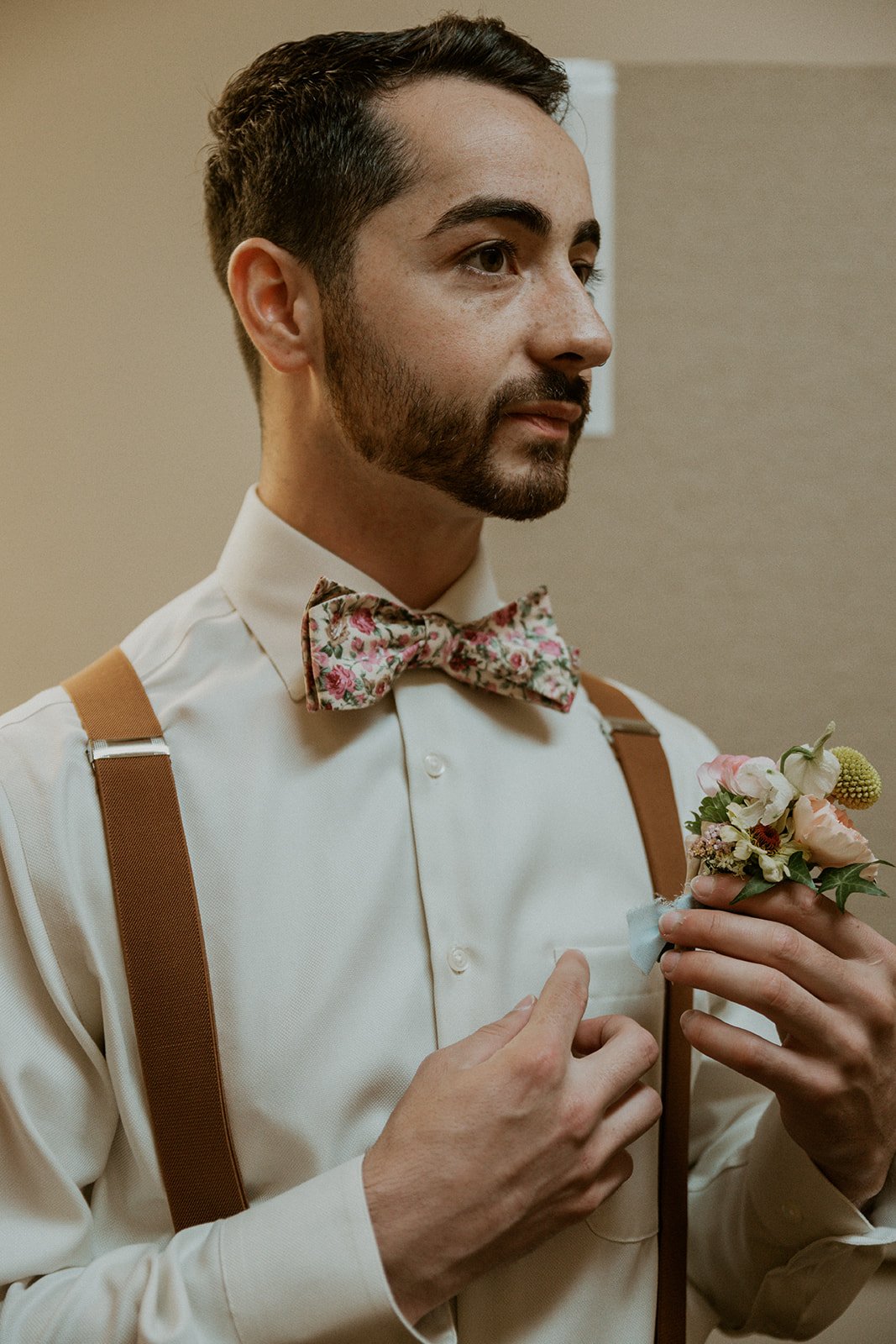 Groomsmen prepares to place his boutonniere to his shirt. 