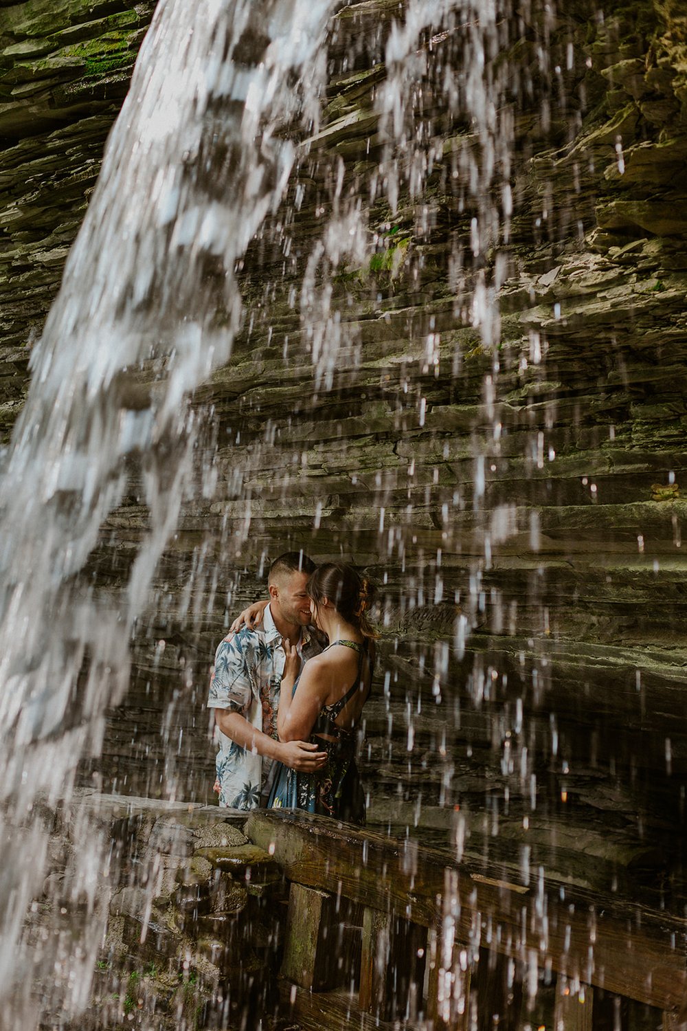 Maggie and Hade hide under the falls sharing an intimate moment together with the sound of the water flowing down the rocks.