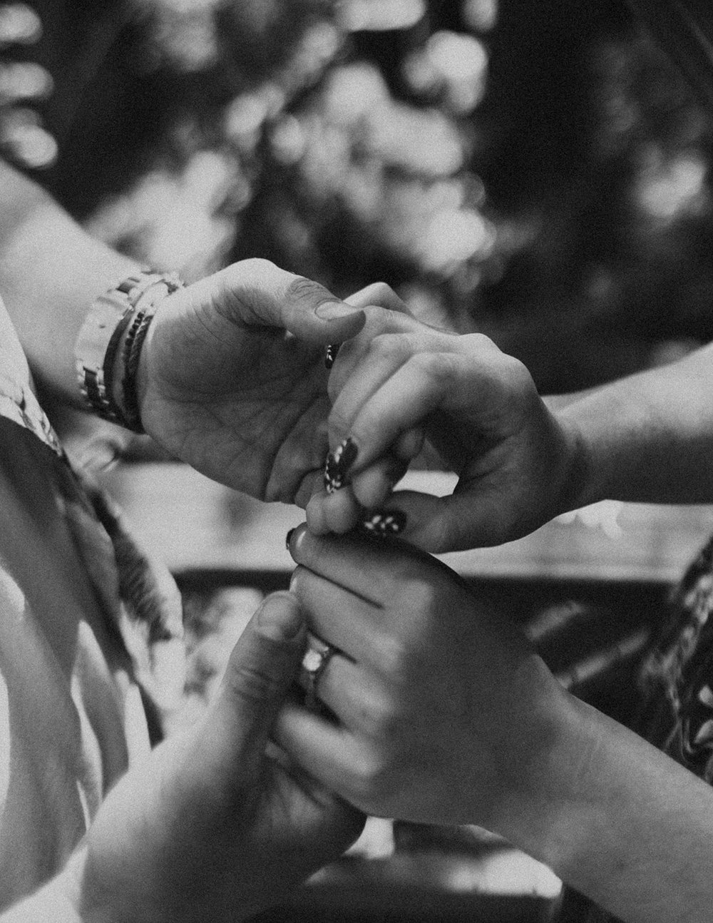 Black and white photo of the couple holding hands admiring the engagement ring.