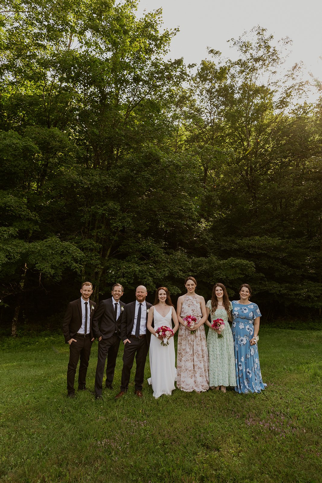 Bridal party pose as a group together with a beautiful green backdrop.