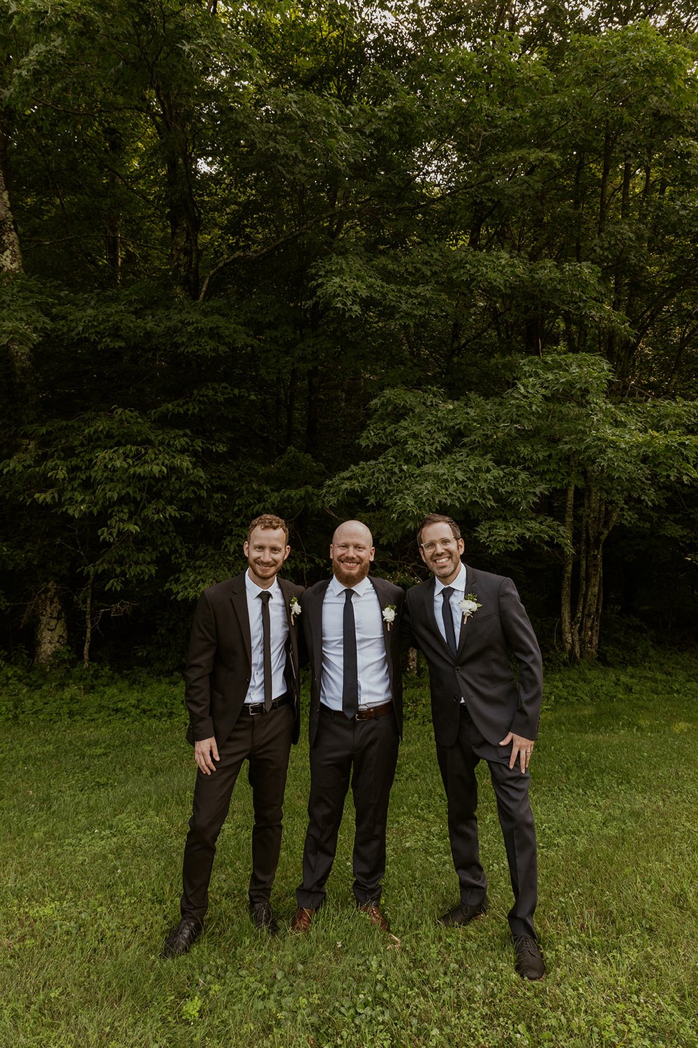 Groomsmen stand side-by-side with big smiles