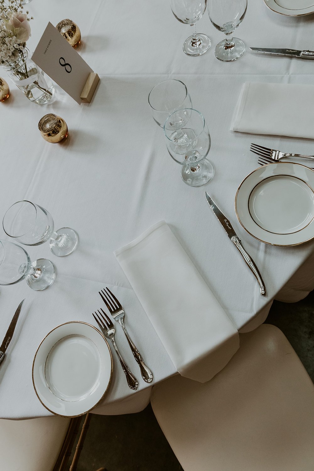 Simple tasteful white and silver table setting with touches of gold.