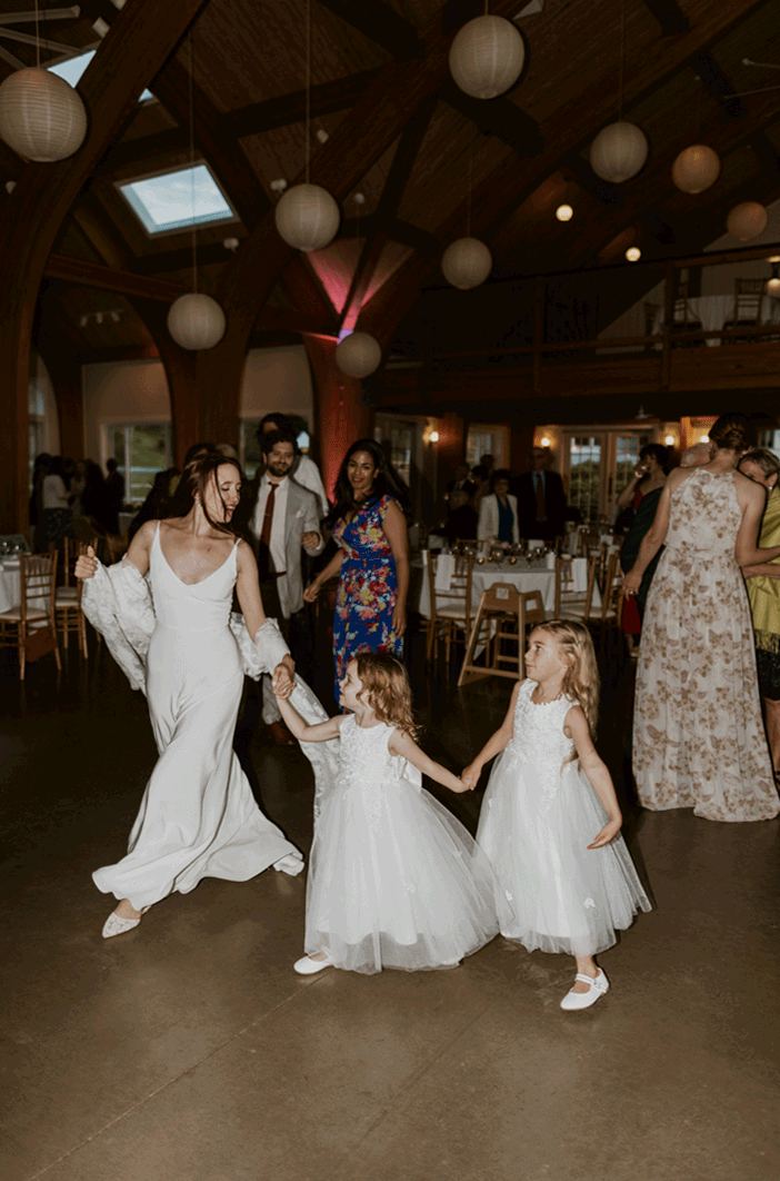 The bride dances in circles with her flower girls. 