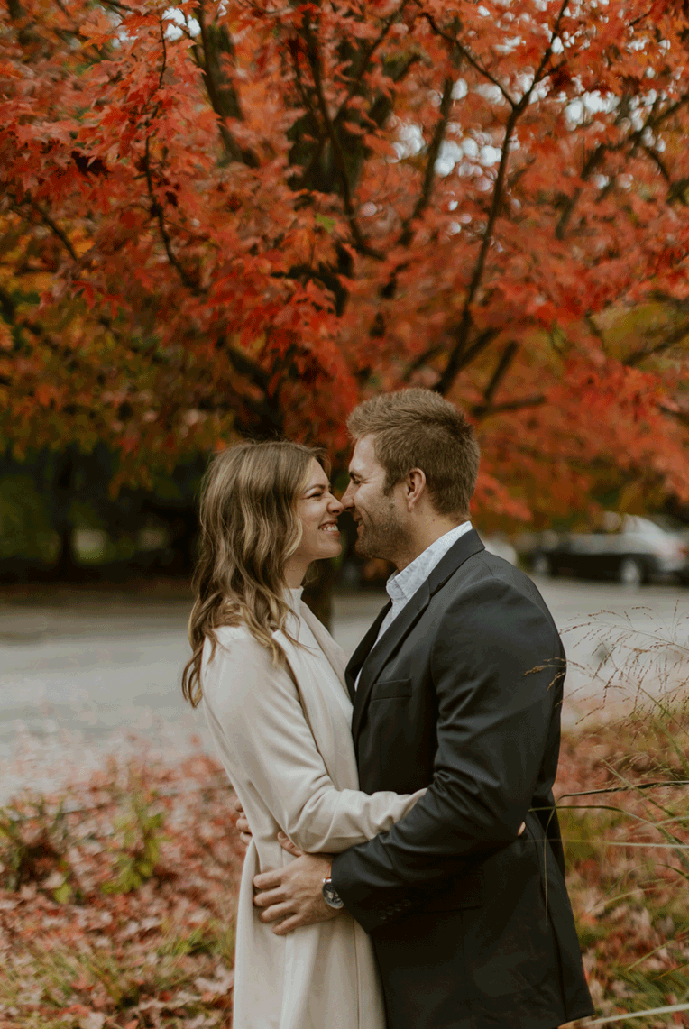  The bride and groom give one another butterfly kisses by rubbing noses withone another under a beautiful red tree.  