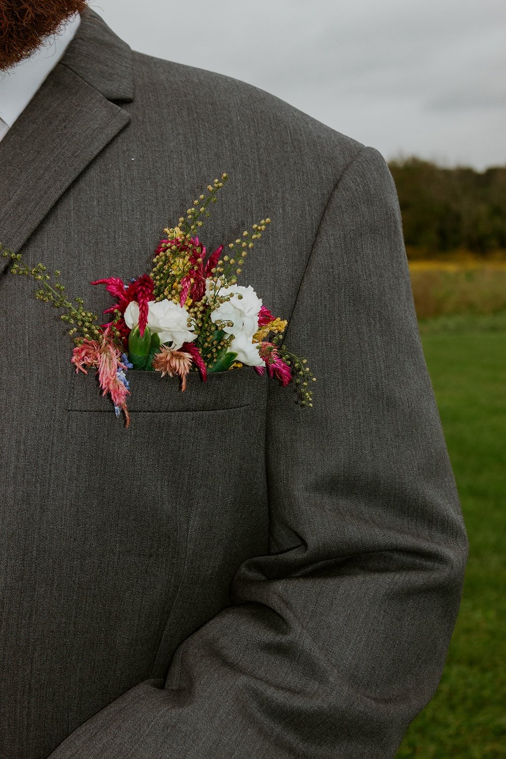 The grooms colorful boutineer dressed with fuchsia, pink and white florals.