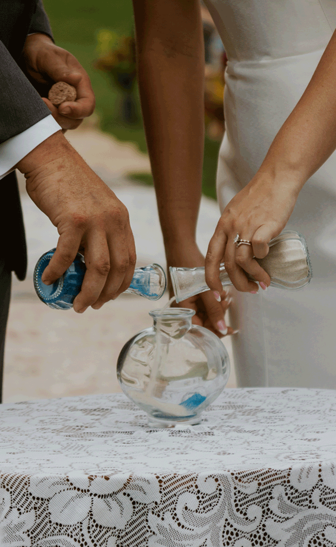 The couple do a unity sand ceremony with blue and white sand. 