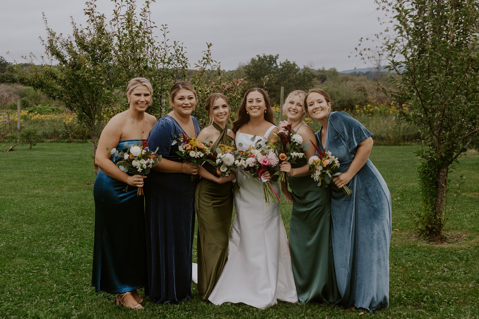 The bride and her maids posing together in beautiful shades of blue and green. 