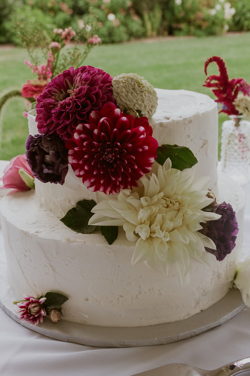 The wedding cake decorated in the bridal florals. A beautiful sleek white cake with bright fuchsia and ivory florals.