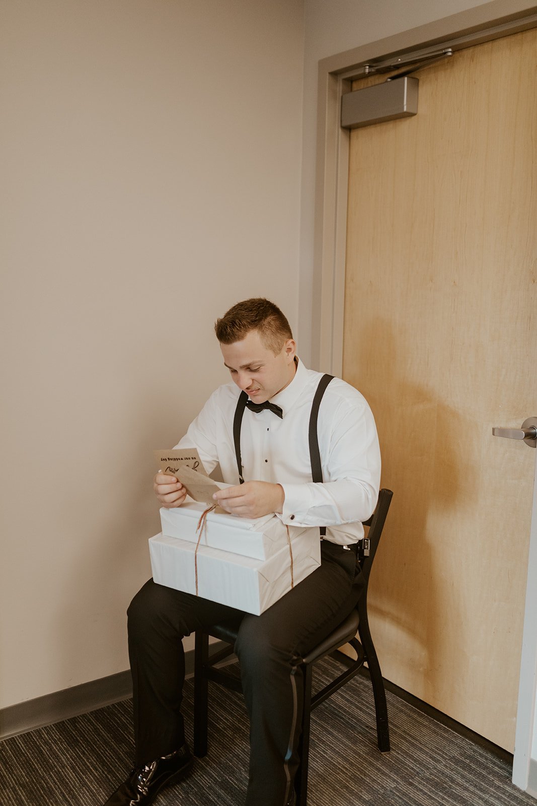 The groom reading his card and opening his wedding gifts from his bride. 