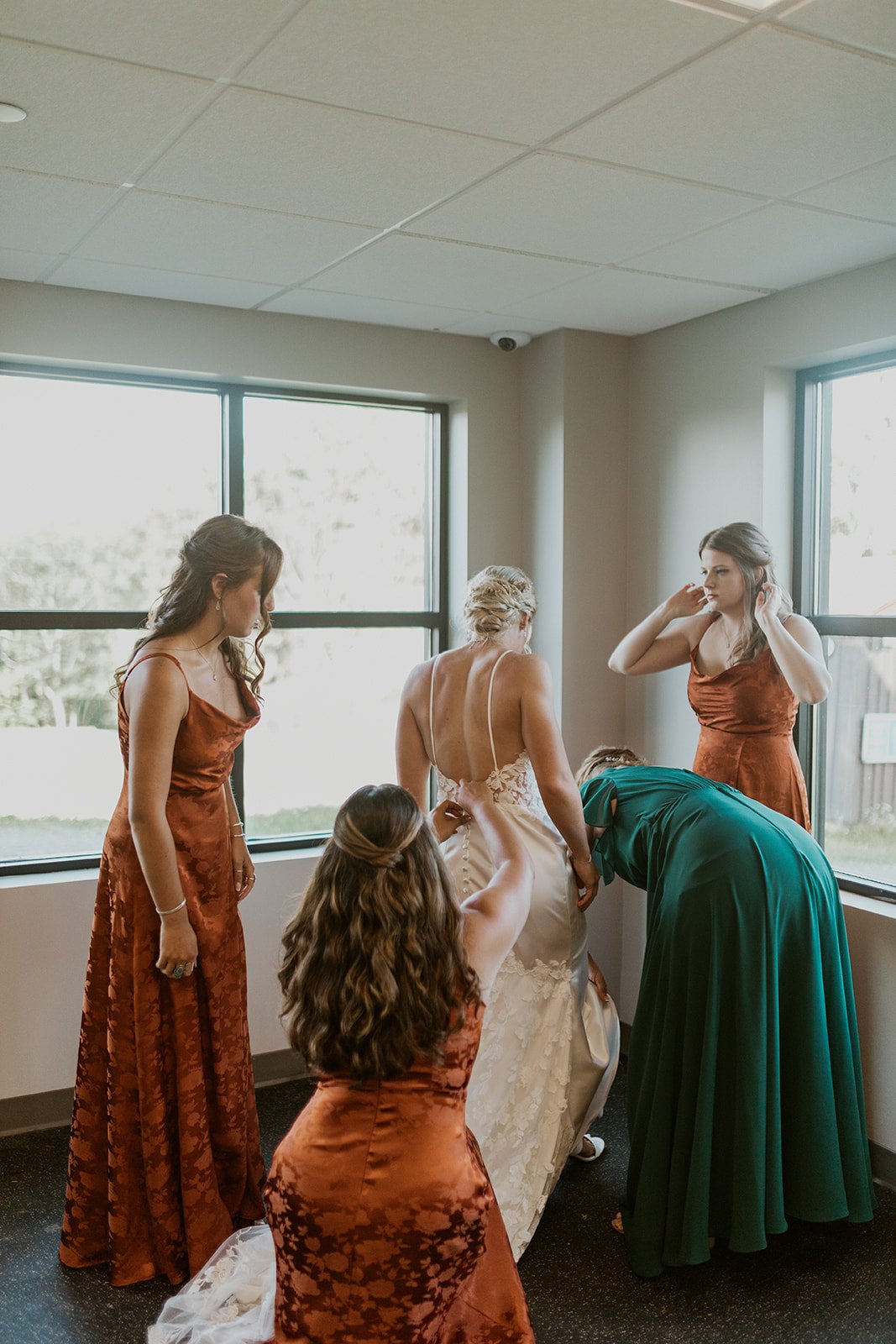 The bridal party assist the bride in getting dressed. 