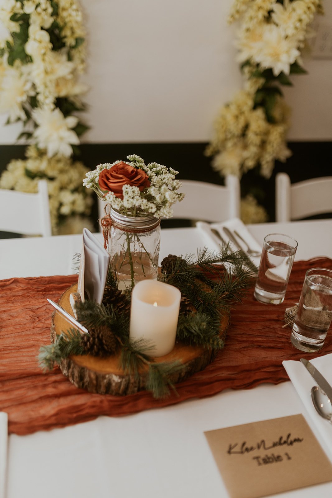 Rustic centerpieces with greenery, candle and floral arrangement. 