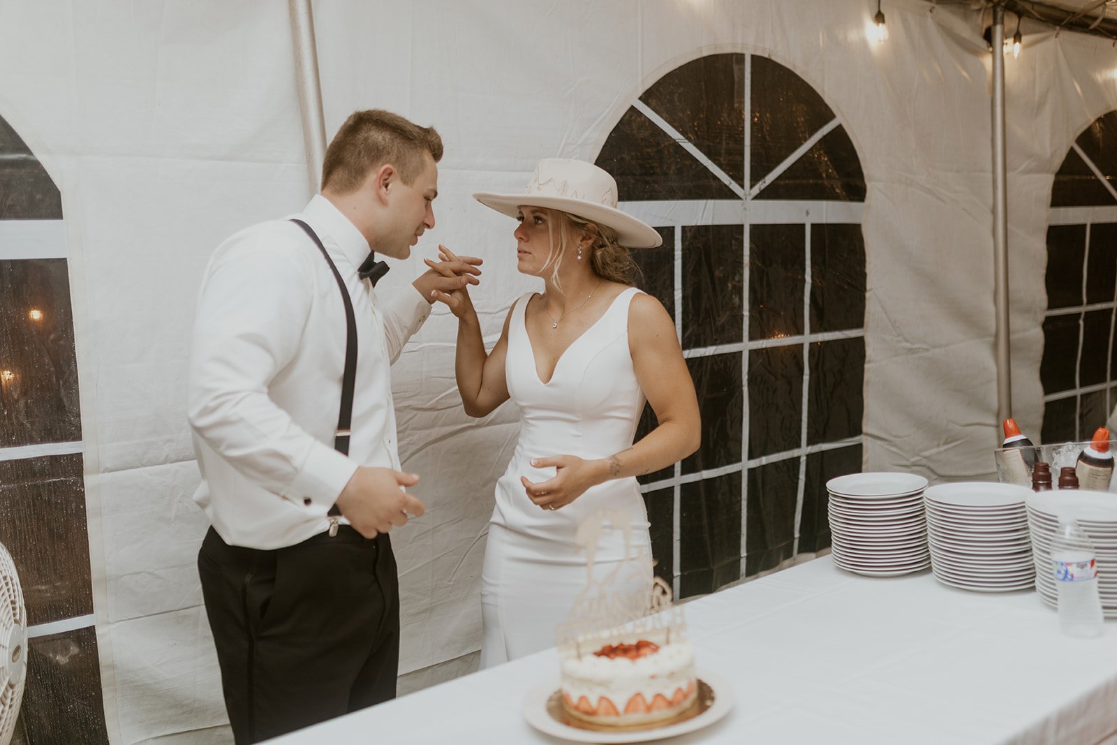 Bride and groom connect hands after sharing their first bite of cake together. 