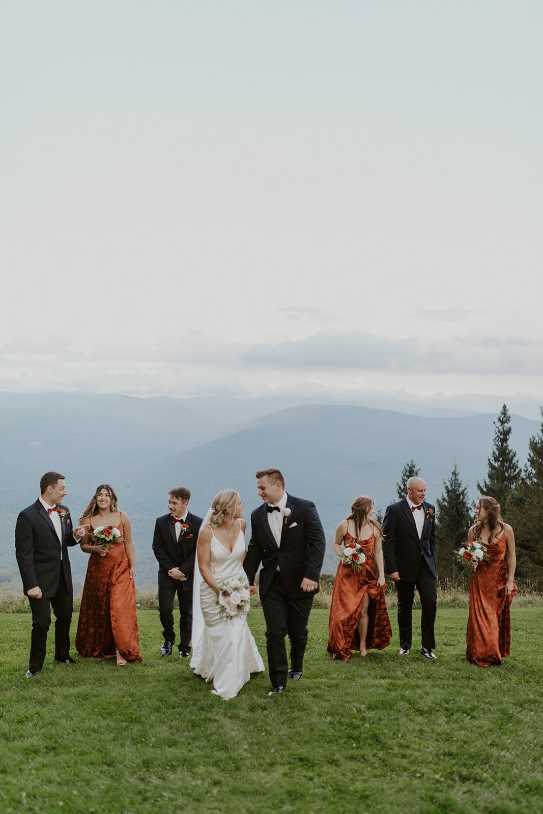 The entire bridal party walk together on the top of the mountain.