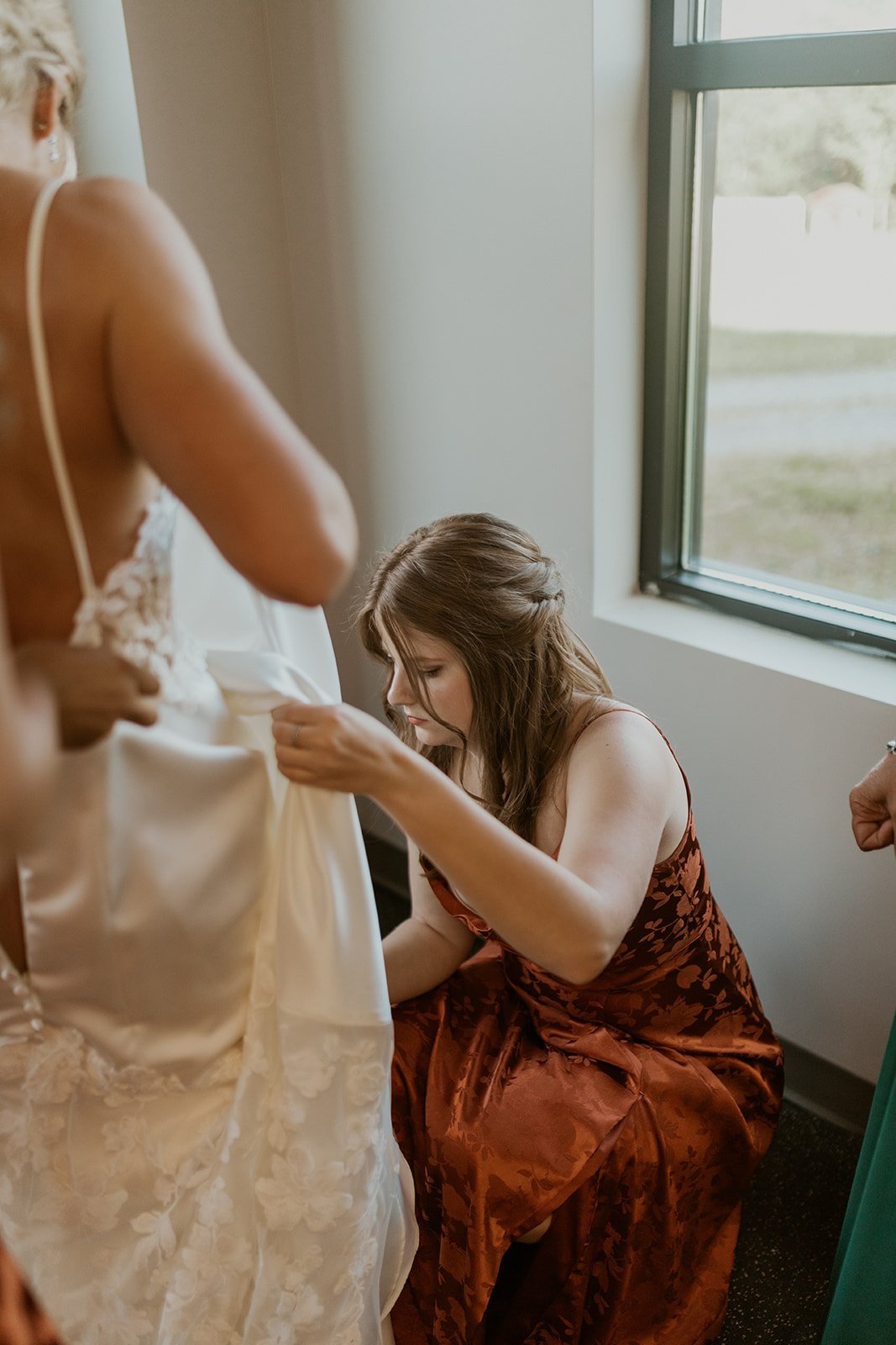 The bridal party assists the bride in getting into her wedding gown. 