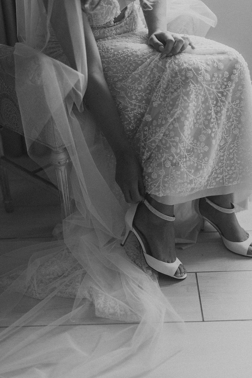 The bride buckles her wedding heel in preparation for her wedding.