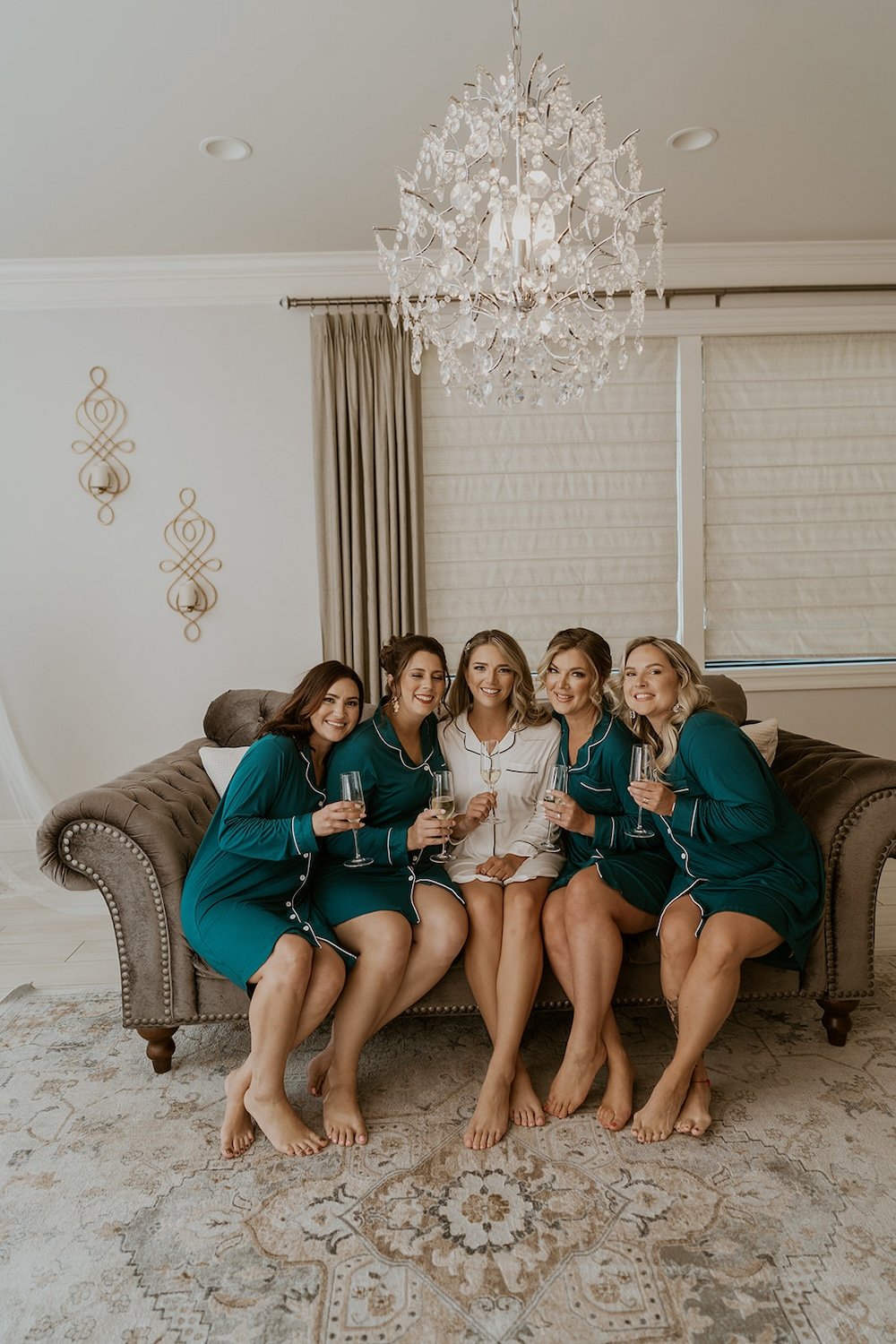 The bridesmaids sit around their bride with champagne.