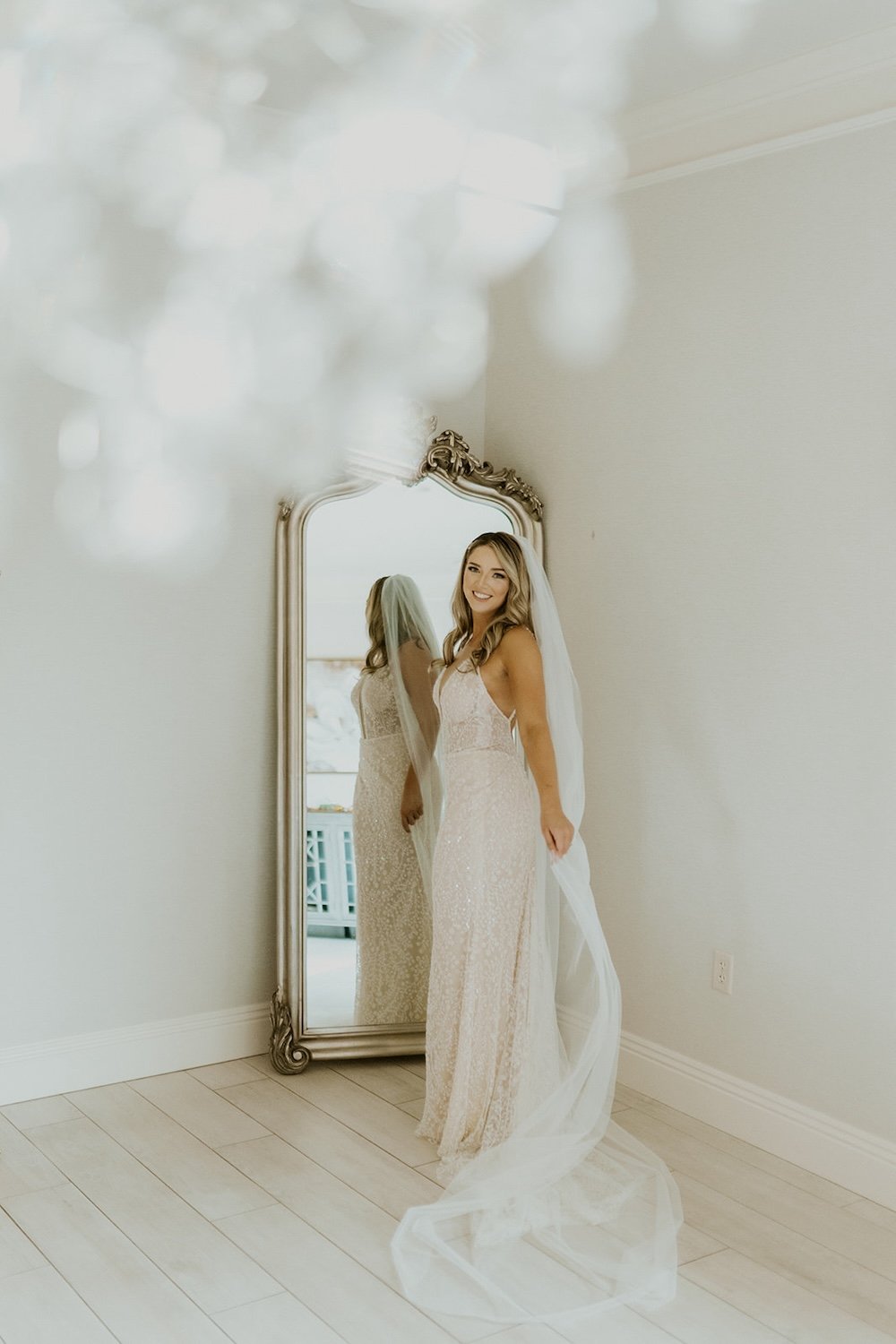 The bride stands infront of the mirror admiring herself.