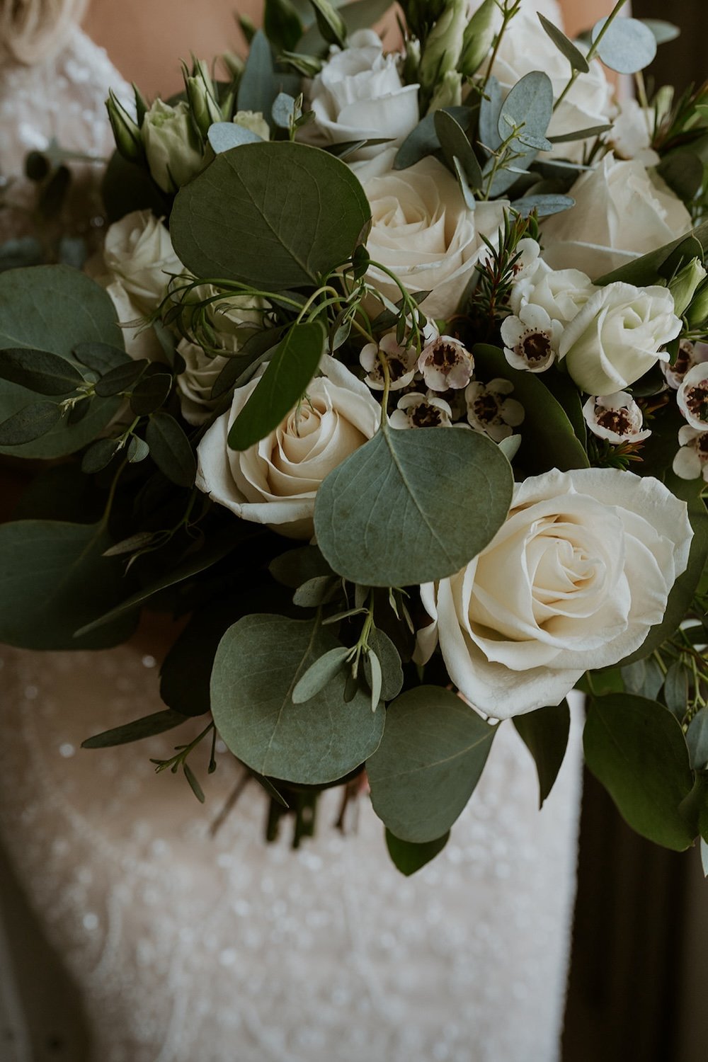 Close up of the bouquet filled with greenery and vibrant white roses. 