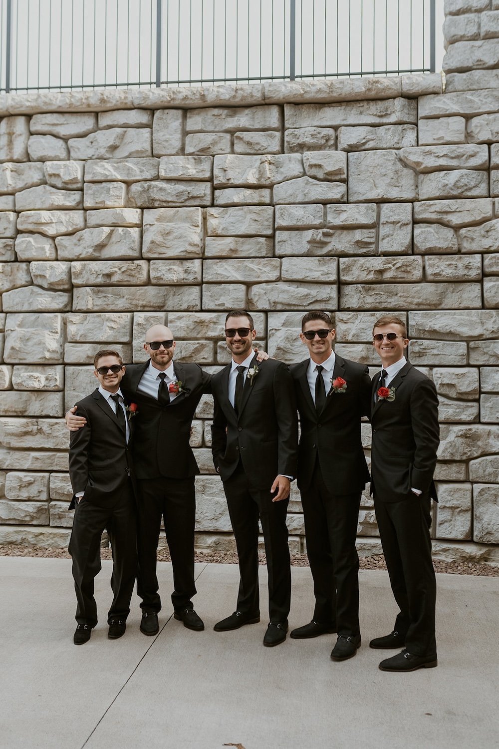 The groomsmen stand together with sunglasses on.
