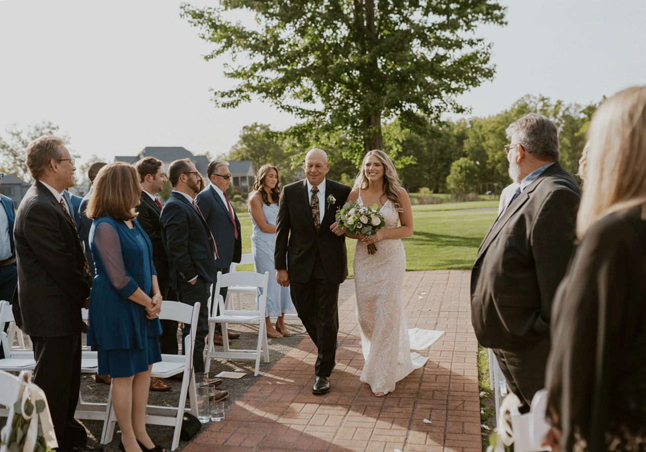 The bride walking up to the gazebo arm and arm with her father. 