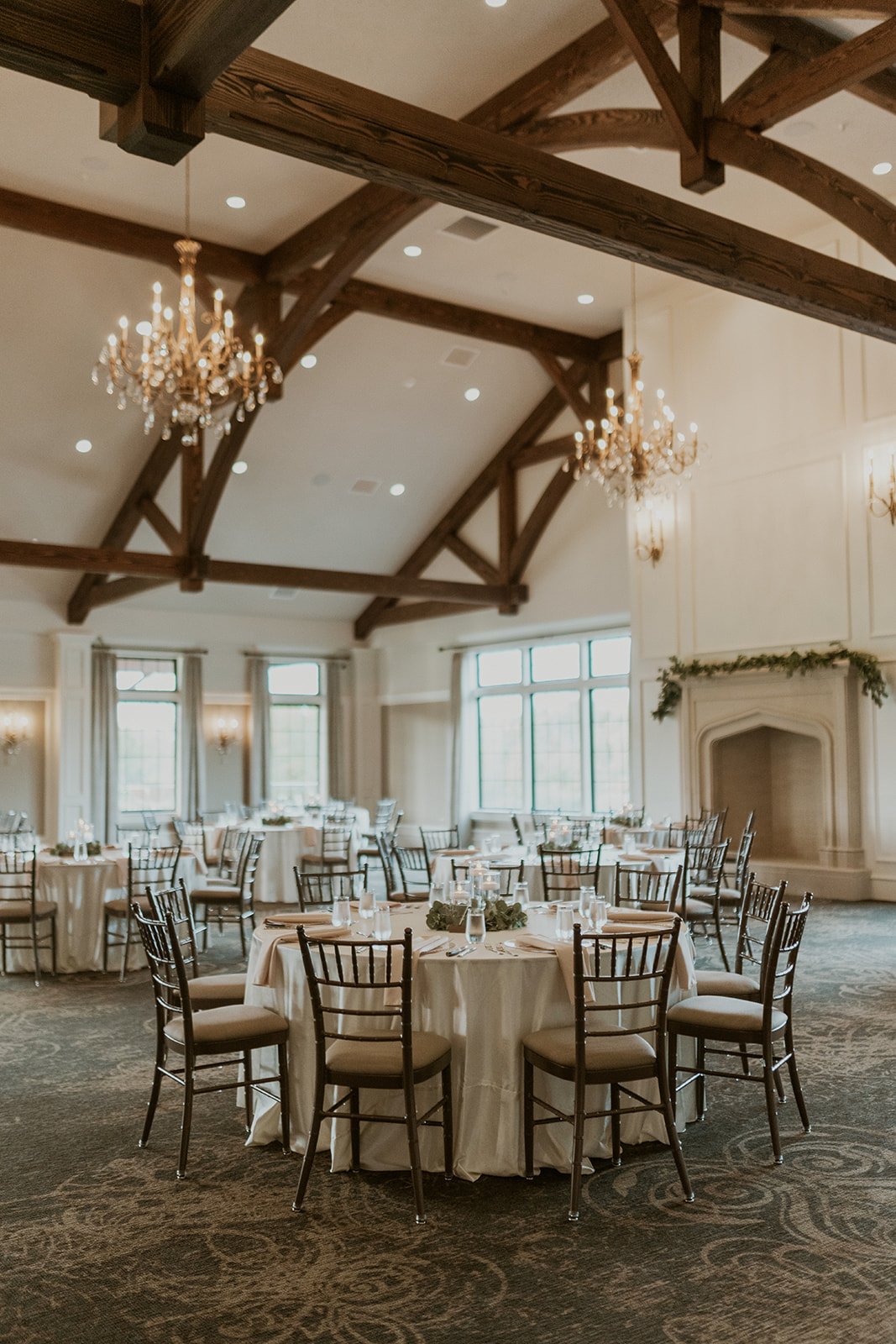 Timber Banks venue decorated with dark wood details, chandeliers, and white linen cover tables. 