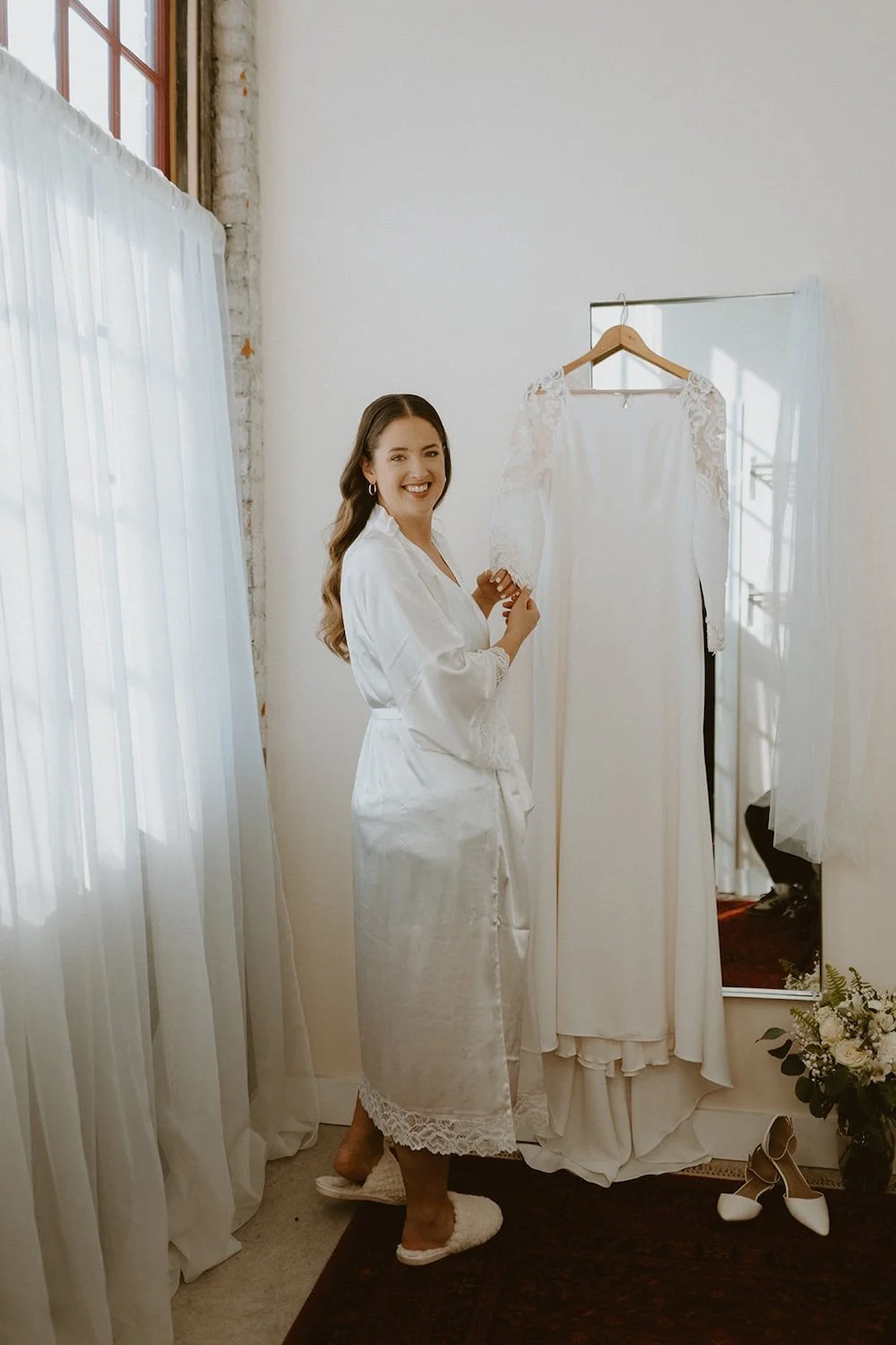 The bride posing with her bridal gown preparing to dress for her wedding ceremony. 
