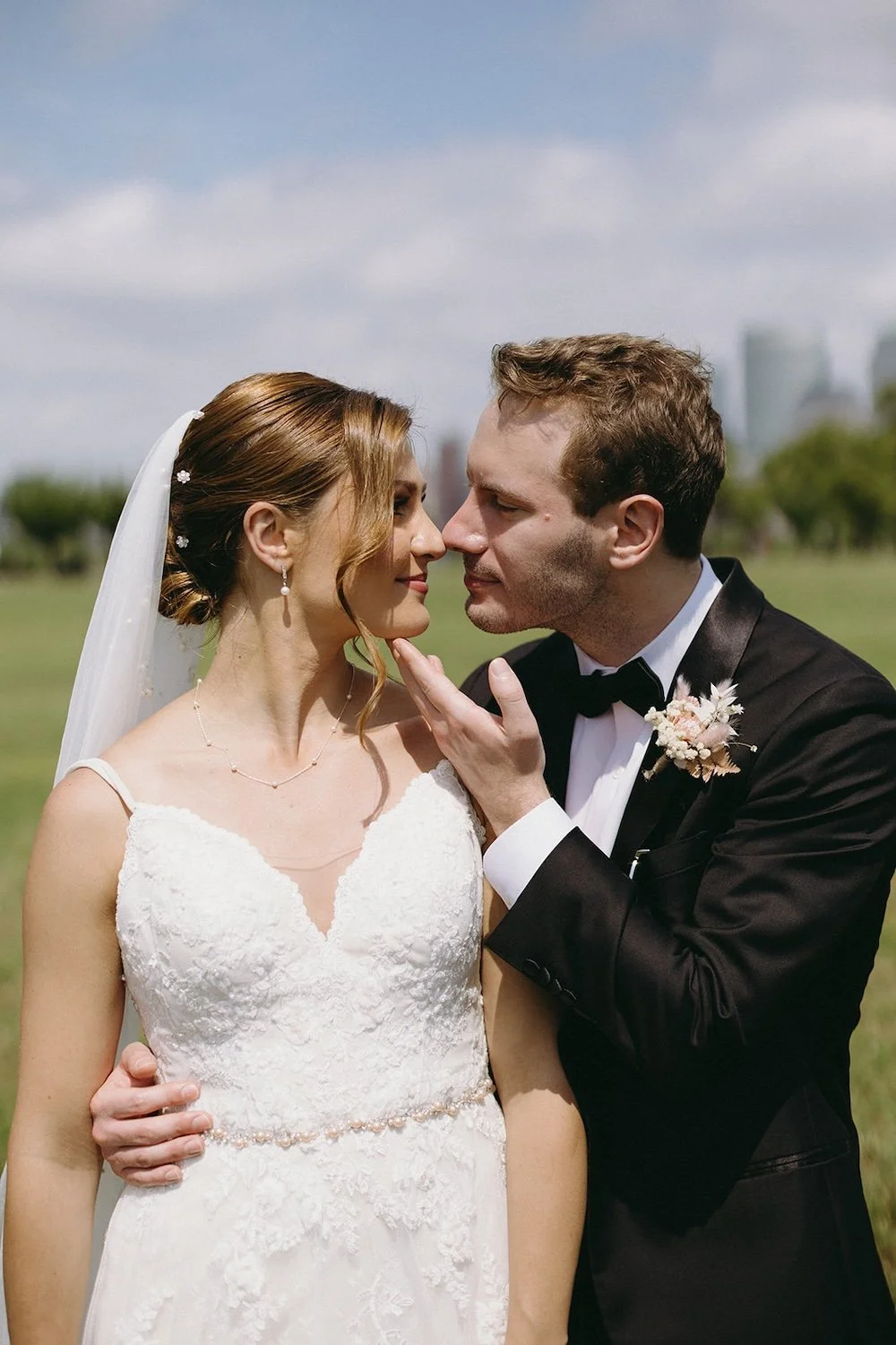 The groom pulls his bride close to sneak a kiss by placing his hand under her chin and holding her close. 