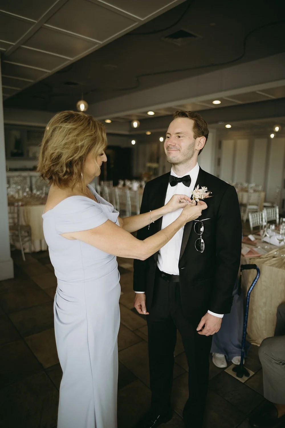 The grooms mother puts the boutonnière on the grooms chest.  