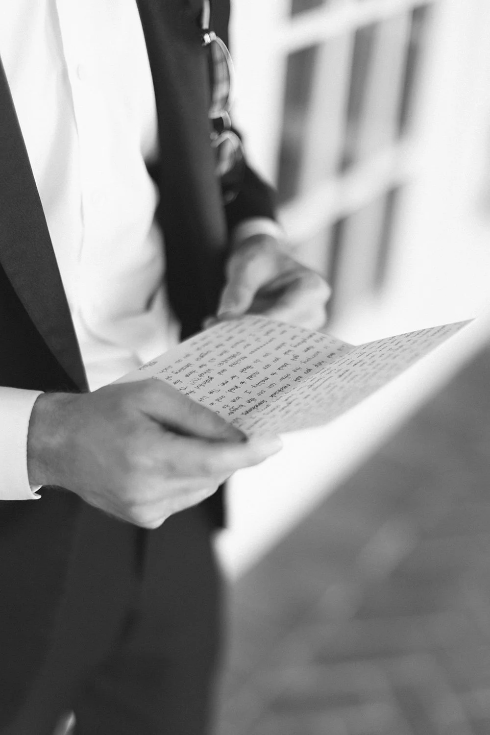 Black and white photo of the groom holding his bride's letter.