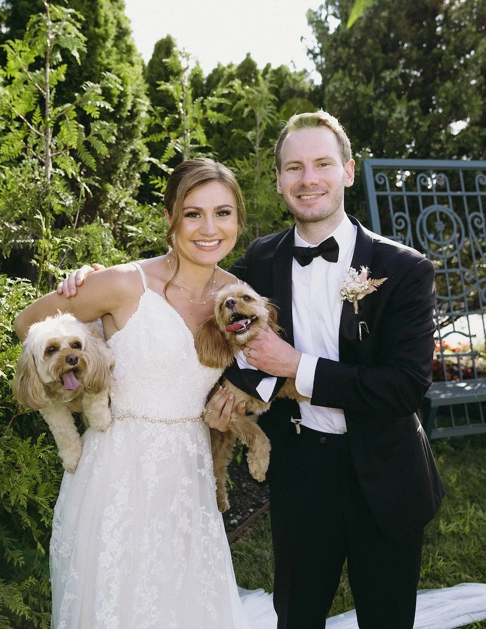 The bride and groom hold their fur babies while posing for a photo. 