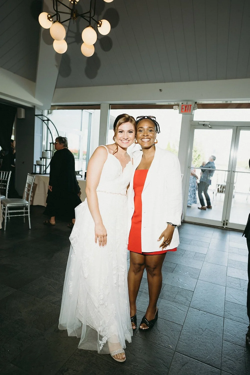 Bride stands posing with a wedding guest. 